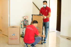 Two movers and packers company people moving a box, working to move with pets.